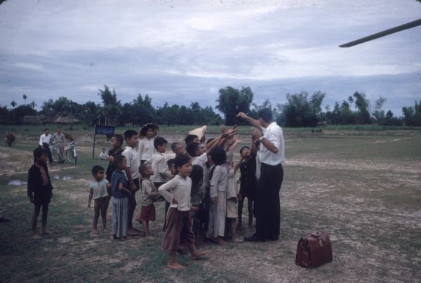 A group of children reaching for something held by a man at the Quin Nhon airport in the mountain region of Vietnam.