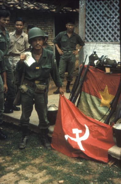 Soldiers from the 5th Division of the Vietnamese Army posing with a Russian flag, a Viet Cong flag, and rifles, seized after a victorious battle near the town of Bien Hoa.