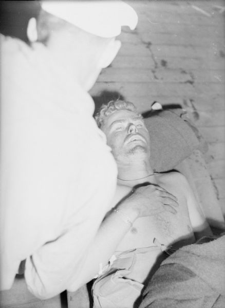 Private first class, John W. Hood being tended to on the deck of the USS <i>Samaritan</i>. Hood suffered an abdominal wound in combat on Iwo Jima.