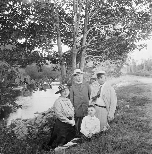 Dr. Joseph Smith poses with friends next to a tree along a rivers edge.
