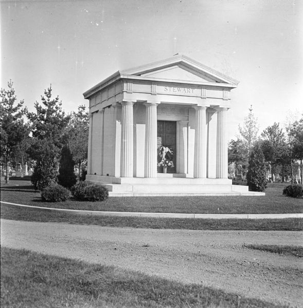 The Stewart mausoleum located in Pine Grove Cemetery. Flowers and a wreath are at the front door of the mausoleum.