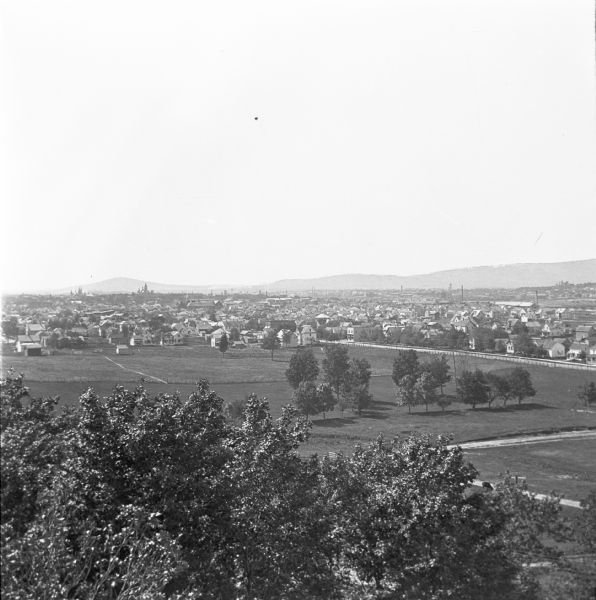 Elevated view of Wausau from the edge of town looking toward residences and businesses. Hills are in the far background.