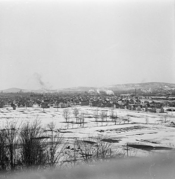 Winter view over fields of town with hills in the far background.