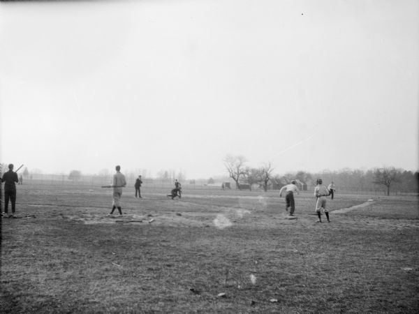 Young boys playing baseball on a baseball field. One of the boys is running towards first base after hitting the ball, while another boy, in the infield, attempts to retrieve the ball.