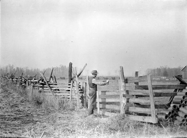 Man working the gate of a split-rail fence.