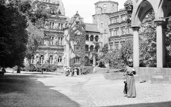 Mary E. Smith walking in the courtyard of Heidelberg Castle.  Several women are standing near the entrance to the building.