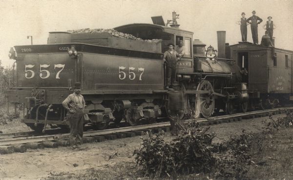 Car number 557 of the Chicago Northwestern railroad at 7th Street. Eight train workers are standing on or around the train.