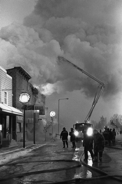 Firefighters battle a fire that engulfed Kruk's Drug Store and Hansen's Department Store. The pharmacy was to change ownership the next day.