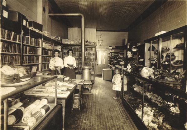 Interior view one of of Hillsboro's early libraries. The library was located in the back of Addie Lind's millinery shop where it connected to an adjoining jewelry shop on Water Avenue. Individuals pictured include Nora Baker, Nell Wagner Butt, Addie Lind and her daughter, Ora Lind.
