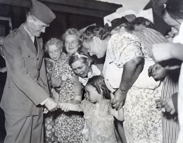 Vice-Admiral Marc A. Mitscher greets a young girl and her family at a parade held in his honor. It was the first time he had visited Hillsboro, his birth place, in a decade. Local and state newspapers covered the event.

