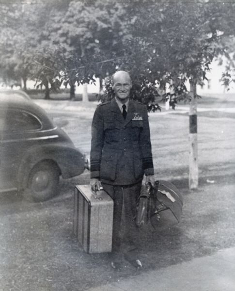 Vice Admiral Marc Mitscher stands with suitcases in hand upon his arrival in Hillsboro. It was the first time in ten years that the military commander had visited his birth place. The town honored Mitscher with a party and parade. Local and state newspapers covered the event.