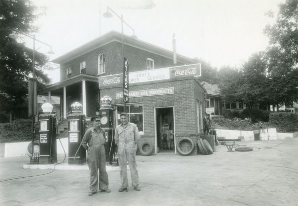 Toots Sullivan (on left) and Emil Picha stand in front of the exterior of the Toot's Standard Gas Station at the intersection of Mill Street and Prairie Avenue.