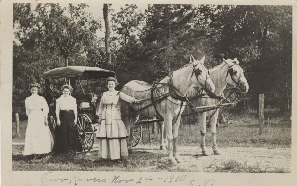 Three smiling women stand beside a horse-drawn carriage near Two Rivers. The horses are wearing knotted, corded fly nets and blinders. The carriage has a covered roof.<p>Clara, wife of Fred Fiebelkorn, wrote this postcard to Mrs. Wm. Fiebelkorn Jr, who was Anna Unglaube, sister of Louise, Mrs. George Koegel. Anna Unglaube Fiebelkorn was living in Cascade, Wisconsin.
