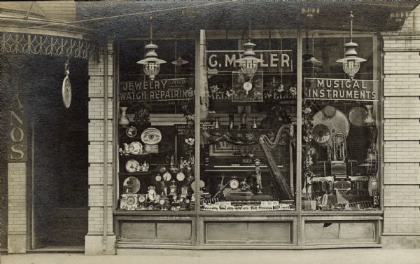 The G. Miller storefront window displays musical instruments as well as clocks and watches. The store is in the Walker's Point neighborhood near South Sixth Street.
