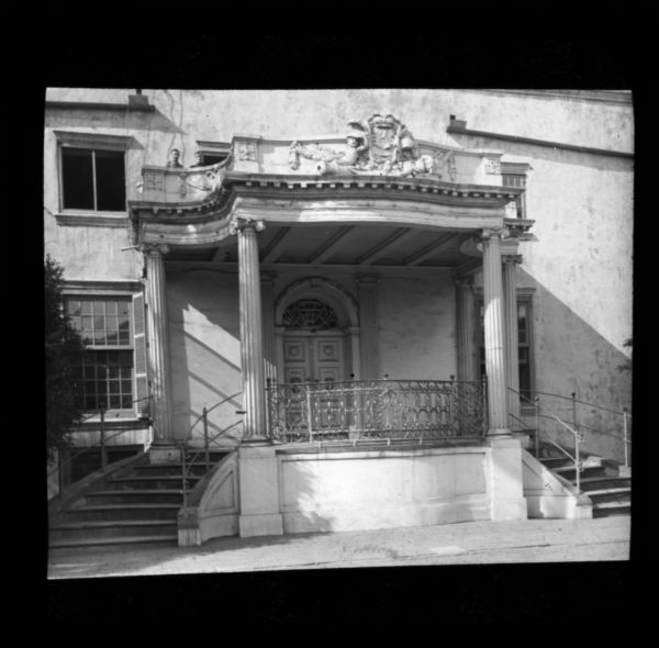 View from inside the grounds of the facade of the Castle of Good Hope in Cape Town, South Africa. A man stands on the balcony above the columned entrance.
