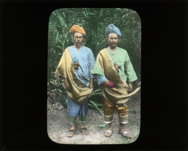 Carrie often described the clothing of the people wherever she was visiting. Here are two men, both wearing head wrappings, gold colored sashes, long sleeve shirts, pants, and sandals.