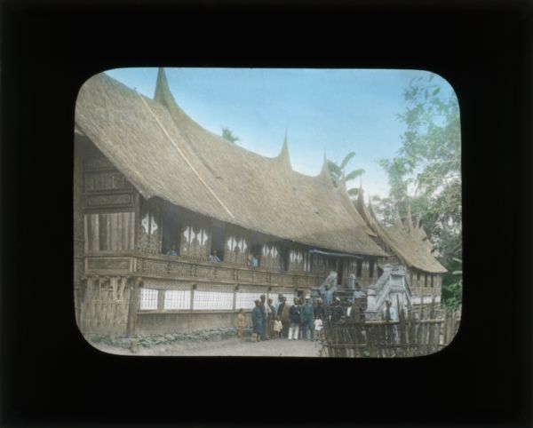 Group of people posing outside of a large building. In her journal from China and the Philippines, Carrie describes the roofs as "horn-like," as seen in this image.
