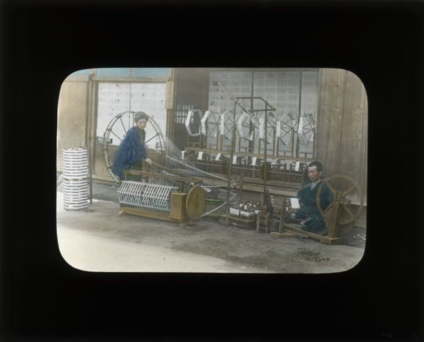 A woman and a man using spinning wheels in a textile factory. In her journal Carrie describes the conditions of these factories in China as crowded and with long hours.