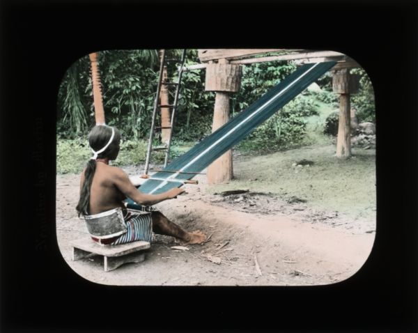 Woman using a loom outdoors. In her journal from Ceylon (now Sri Lanka) she records: "The women braid the fibres together making a crude mat of them. The trunks of the trees are set up in the form of a house and these mats are hung up to make the walls."