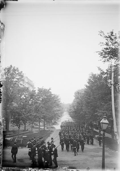 A military Battalion marching up Langdon Street. The Memorial Union is on the left behind trees.