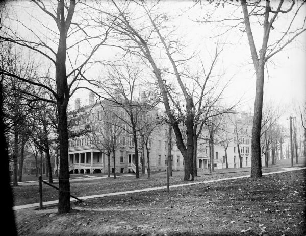 University of Wisconsin-Madison Ladies' Hall from the northeast. A fence runs in the foreground, and with trees are on the lawn surrounding the building.