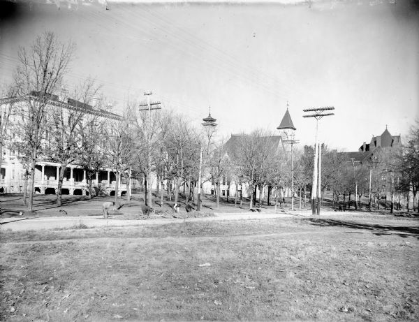 A southwest corner view of the University of Wisconsin campus, from University Avenue just east of Park Street. A group of men are working in the road among piles of dirt and rock.