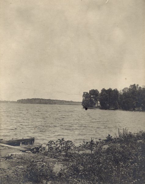 View from shoreline across Lake Mendota towards Maple Bluff. There are pilings in the foreground on the left.
