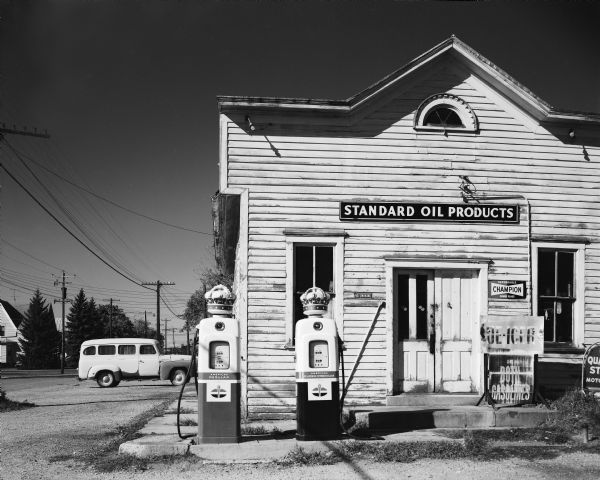 Gasoline station, with Standard Oil Products and Champion signs, in old false front building.