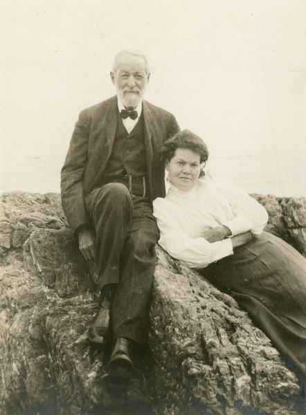 Unidentified elderly man with younger woman sitting on rocks.