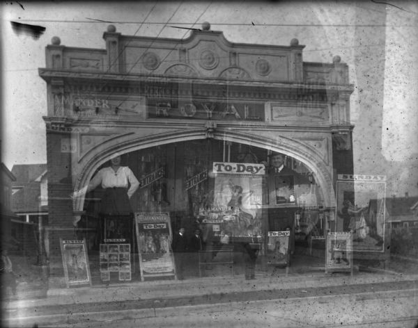 Double exposure of two views of the exterior of the Royal Theater at 407 Atwood Avenue in the Schenk-Atwood Neighborhood (address now 2142 Atwood). The large image shows a man (possibly Louis Schoelkopf) and a woman (possibly Emma Schoelkopf), posed in the entrance of the theater. The woman has her hand on an iron railing, and the man has his arm draped over a sandwich board movie advertisement. The smaller image shows three men standing under the theater arch among placards for the "Salamander" show. This building is now the site of Wilson's Bar. The Royal Theater may have been designed and built by Madison architect Ferdinand Kronenberg.
