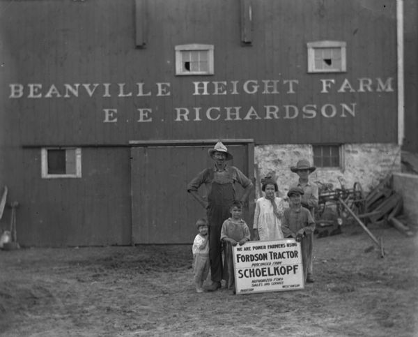Group portrait of a farmer and five children posing with a sign that reads: We Are Power Farmers Using Fordson Tractor Purchased from Schoelkopf, Authorized Ford Sales and Service, Madison Wisconsin." The barn behind them is a sign that reads: "Beanville Height Farm, E. E. Richardson." The man is wearing overalls and a straw hat.

Fordson tractors were manufactured by the Henry Ford Company from 1916 through the 1930s all over the world, but only sold from 1918-1928 in the United States.