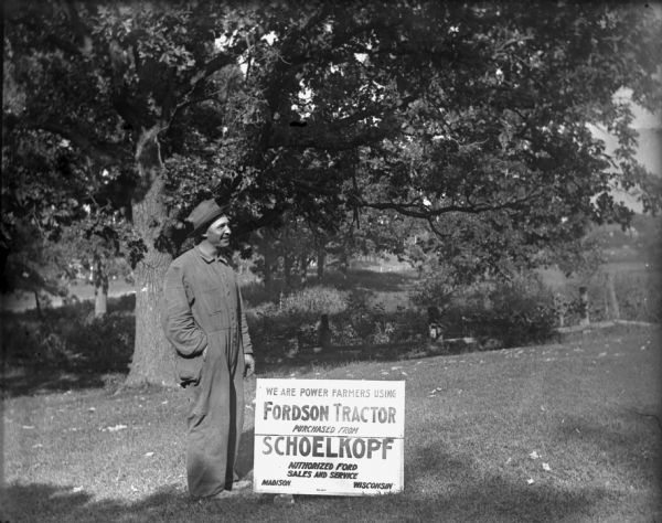 A smiling man dressed in coveralls and a hat stands on a lawn next to a sign that reads: "We Are Power Farmers Using Fordson Tractor Purchased from Schoelkopf, Authorized Ford Sales and Service, Madison, Wisconsin."

Fordson tractors were manufactured by the Henry Ford Company from 1916 through the 1930s all over the world, but only sold from 1918-1928 in the United States.