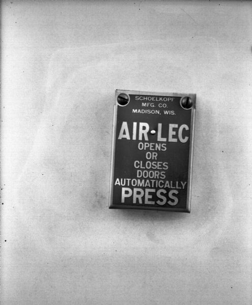 Air-Lec automatic door opening button, which reads: "Schoelkopf Mfg. Co. Madison, Wis. AIR-LEC Opens or Closes Doors Automatically PRESS."