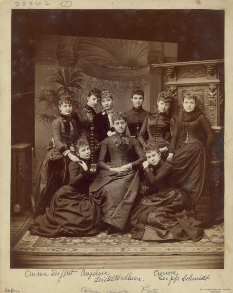 Emma Seipp, third from left in second row, poses with eight other young women against a carved studio prop and painted backdrop. Two of the other women, Emma Seiffert and Angelina Leicht Madlener, are identified. The women are wearing finely tailored dresses. Emma Seipp (1868-1942), the eldest child of Conrad and Catherine Seipp, later married Dr. Otto Schmidt and together they owned Black Point Estate.