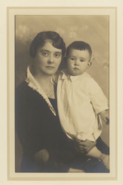 Waist-up, seated portrait of Alma Schmidt Petersen holding her son, William O. Petersen. She is wearing a dark dress with a lace collar, and a beaded necklace. Alma was the granddaughter of Conrad Seipp, Chicago brewer and builder of Black Point.