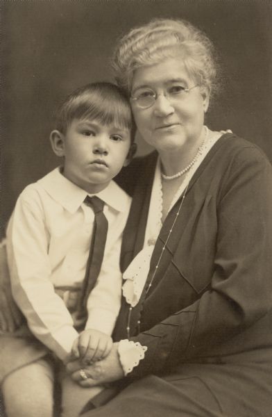 Three-quarter length, seated portrait of Mrs. Edward Petersen with her grandson, William Otto Petersen (1926-2012). Mrs. Petersen is wearing a dress with lace trim, and two pearl necklaces.