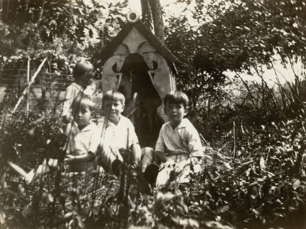 The Petersen brothers, from far left William Otto, Conrad Schmidt, and Edward William, with an unidentified boy (probably a cousin) pose in front of a small shed which served as a shelter for pet goats. The children cared for the goats during the summers they spent at Black Point Estate. Wooden cut-outs of goats form the front of the shed.