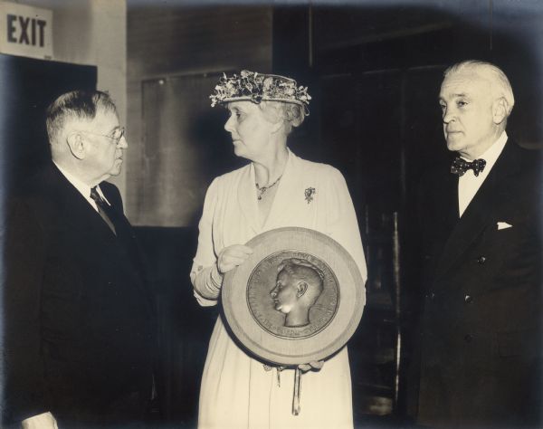 Alma Schmidt Petersen, center, holds a plaque with a relief portrait of a woman's head in profile, and the inscription "Louise de Koven Bowen, President of the Board Hull House 1935-44." On her left is former U.S. Secretary of the Interior, and on the right is banker and philanthropist Marshall Field III. Petersen, the granddaughter of Chicago brewer Conrad Seipp and owner of Black Point Estate, served for many years on the board of Hull House.