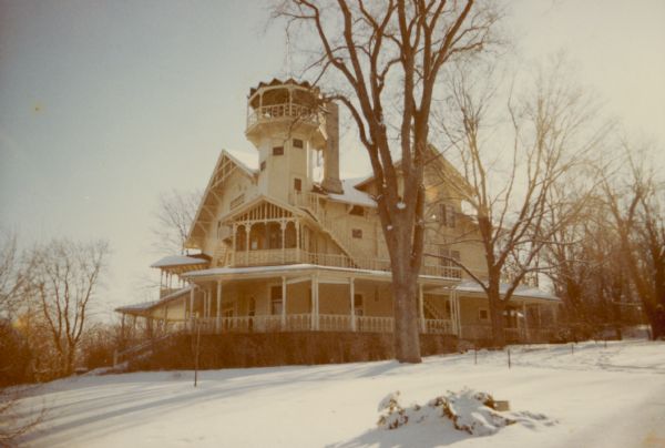 A winter view of the main house at Black Point Estate from the northwest shows the distinctive tower and multiple porches. One of the large chimneys is visible behind the tower. The house, overlooking Geneva Lake, was built by Chicago brewer Conrad Seipp in 1888 and initially named the Loreley.