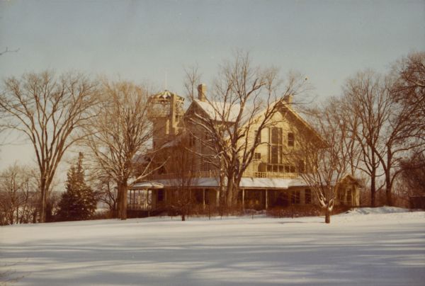 A winter view of the main house at Black Point, seen from the rear (south), showing the distinctive tower, chimneys and porches. A small one-story addition, right, stands where the original two-story "laundry house" was located. There is a glimpse of Geneva Lake on the left. The house was built by Chicago brewer Conrad Seipp in 1888 and initially named the Loreley.