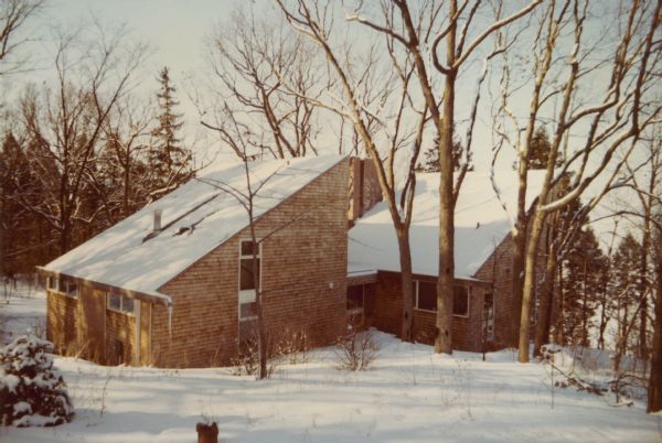 A winter view of the William O. Petersen house on the grounds of Black Point Estate, showing the two shed-roofed wings of the house which overlooks Geneva Lake (on the right). The house is clad with wood shingles and is located south of the original 1888 summer home of Chicago brewer Conrad Seipp.