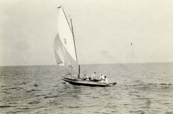 View across water of Dr. Otto L. Schmidt, second from right, sitting at the helm of the "Senta," with a crew of four. Dr. Schmidt was married to Emma Seipp, daughter of Chicago brewer Conrad Seipp. The Schmidts were owners of Black Point Estate.
