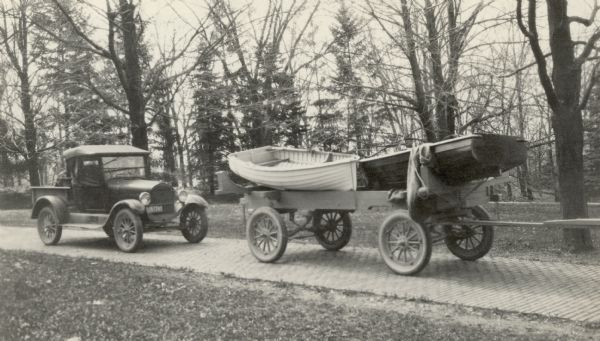 A pickup truck parked on the brick drive near the main house at Black Point Estate. Two boats rest on a trailer parked in front of the truck.