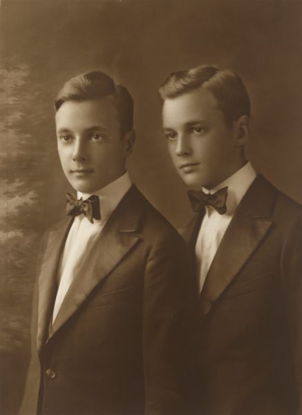 Waist-up studio portrait in front of a painted backdrop of twins Otto, left, and William Madlener, sons of Albert F. and Elsa Seipp Madlener. The boys are wearing suits and bow ties.