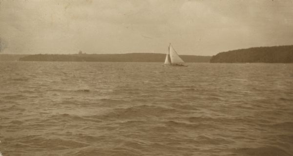 View across water towards the <i>Black Point</i> sailing on Geneva Lake. Yerkes Observatory is in the far background.