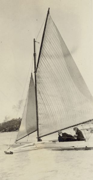 Kurt Ruedebusch and Joe Mills pose in Ernst Schmidt's iceboat on frozen Lake Mendota. Ernst Schmidt was an undergraduate student at the University of Wisconsin at the time.