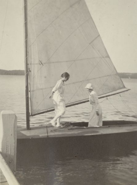 Sisters Alma, in dark glasses, and Tessa (Clara Theresa) Schmidt aboard the "Water Witch" at the pier at Black Point. Both women are wearing long white dresses; Tessa sports a hat. The women were granddaughters of Chicago brewer Conrad Schmidt, who built Black Point in 1888.
