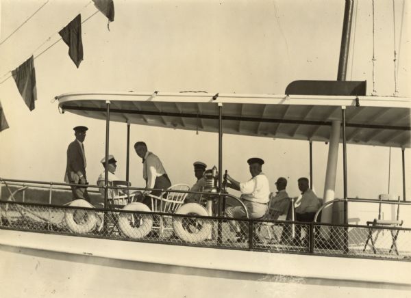 The judges for the 1925 Inland Lake Yachting Association Regatta held at Lake Geneva are shown aboard Commodore Colonel William Nelson Pelouze's steamer "Fladora." A description written by Ernst Schmidt and kept with the photograph identifies the judges: "From the bow, reading aft: Addin P. Kaye of Lake Geneva and Sarasota, Florida - Mr. Powelk of Milwaukee, father [Dr. Otto Schmidt], and I do not know who the next person is — Mayor Thompson of Chicago at the wheel — R.A. Hollister of Oshkosh and J.T. O'Brien of Oshkosh and also secretary of the association. The dates of this regatta were August 17 to August 21, 1925."