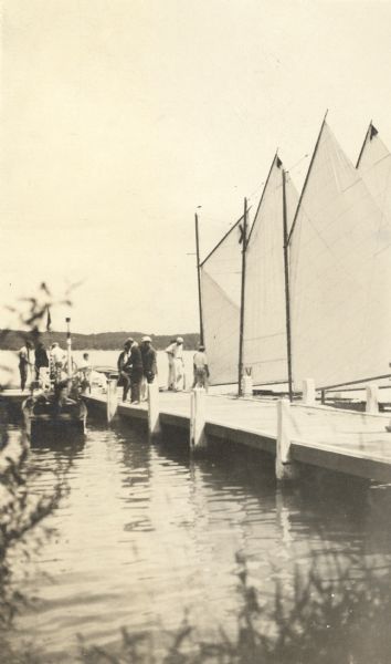 A description of this photograph written by Ernst Schmidt reads, "The Black Point Pier on Saturday, July 15, 1922, just before the start of a class "C" race." There are several men standing on the pier, with sailboats moored on the right. There is a motorboat moored to the pier on the left.