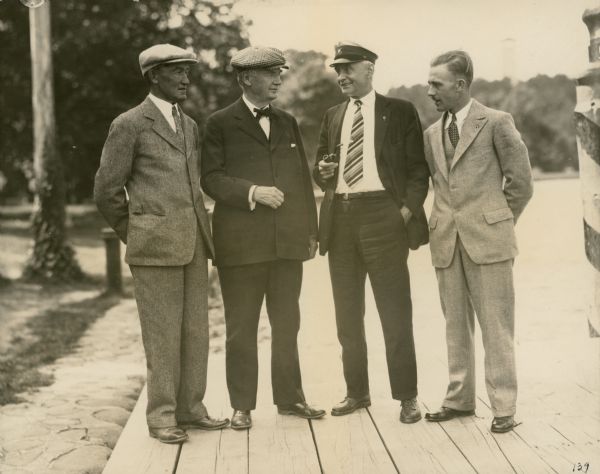 Four well-dressed gentlemen stand on a pier. A description of the photograph written by Ernst Schmidt reads: "This picture was undoubtedly taken at the 1930 I.L.Y.A. [Inland Lake Yachting Association] Regatta at Neenah, Wisconsin. Left to right are: Addin P. Kaye, one of the judges, of Lake Geneva, Wisconsin and Sarasota, Florida — Father [Dr. Otto L. Schmidt] — Ed. Rising of Chicago one of the judges and Edwin Brismaster of Oshkosh, Wisconsin the former secretary of the Inland Lake Yachting Association.
